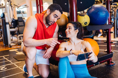 Portrait of couple in love at gym watching exercise on mobile phone