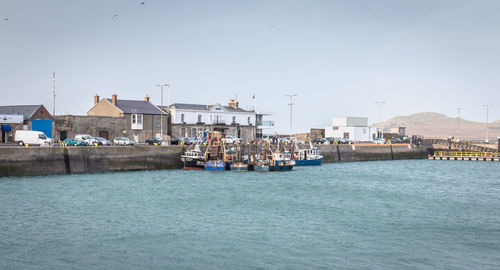 Buildings by sea against clear sky