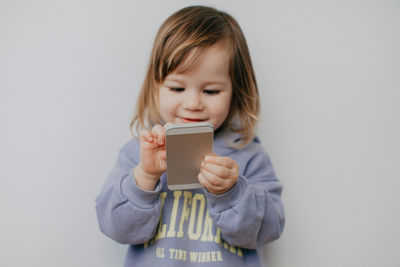 Portrait of cute girl playing with toy against white background