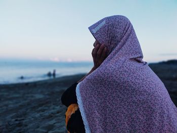 Midsection of woman at beach against sky