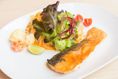 High angle view of fish with salad in plate on table