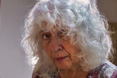 Portrait of an elderly grey-haired curly woman with long hair.