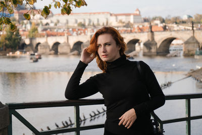 Beautiful woman standing by railing against bridge