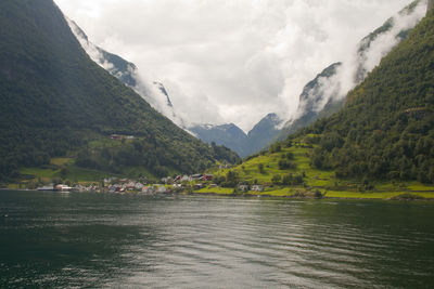 Scenic view of river by mountains against sky