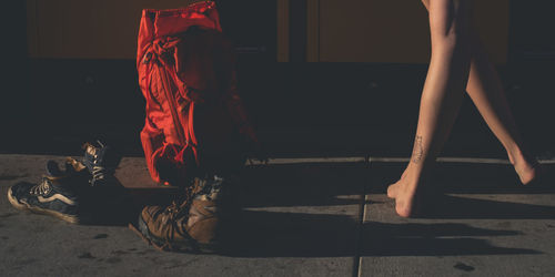 Low section of woman dancing by shoes and backpack on footpath