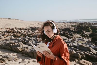 Young woman standing at beach against clear sky