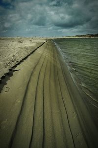 Scenic view of beach against cloudy sky