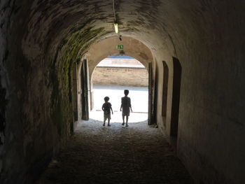 Rear view of people walking in tunnel