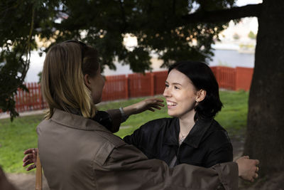 Smiling woman embracing female friend at park