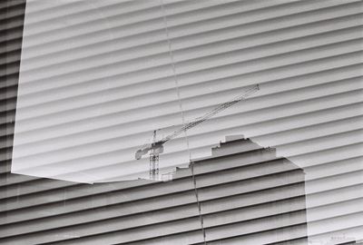 Reflection of crane and building on glass window with lines