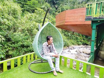 Rear view of woman sitting on railing