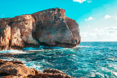 Rock formation in sea against sky