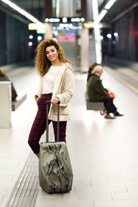Portrait of smiling young woman standing on subway station