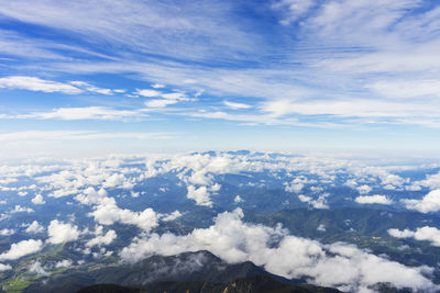 Aerial view of clouds over mountains against blue sky