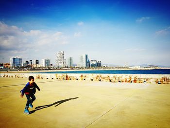 Full length of man skateboarding on city against sky