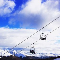 Low angle view of overhead cable cars against sky