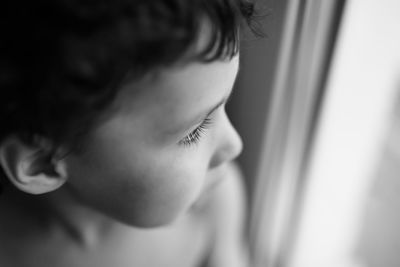 Close-up of boy looking through window