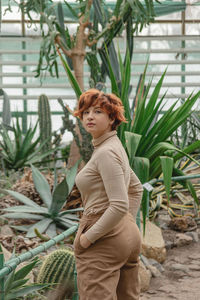 A beautiful plus size girl enjoying standing among the green plants of the greenhouse.