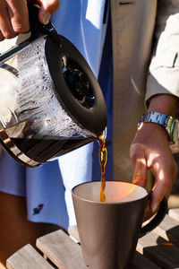 Midsection of man pouring coffee into cup