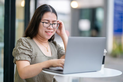 Portrait of young woman using laptop at home
