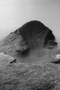 Rock formation in sea against sky