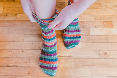 Low section of woman wearing multi colored socks on floorboard