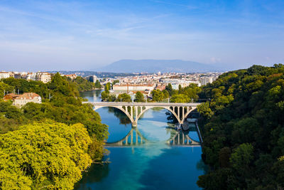 Bridge over river amidst cityscape against blue sky