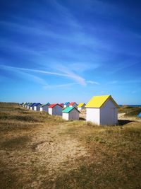 Beach huts on field against blue sky