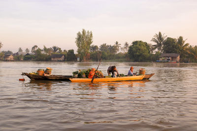 People on boat in river against sky