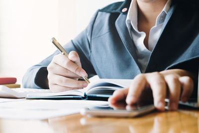 Midsection of woman reading book on table