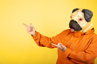 Portrait of young woman with dog against yellow background