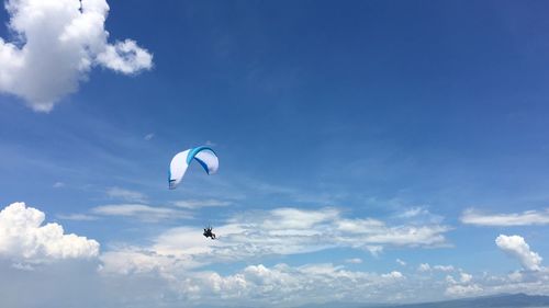 Low angle view of paragliding against blue sky