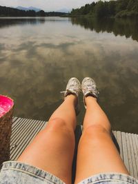Low section of woman relaxing against lake