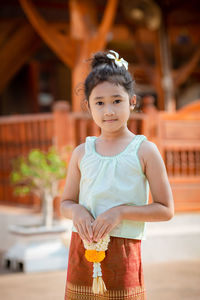 Portrait of smiling young woman standing against blurred background