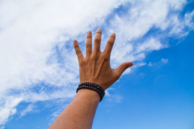Cropped hand against sky