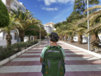 Rear view of woman with backpack standing on footpath