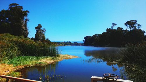 Scenic view of lake against clear blue sky