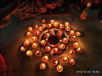 High angle view of hand holding illuminated candles in temple