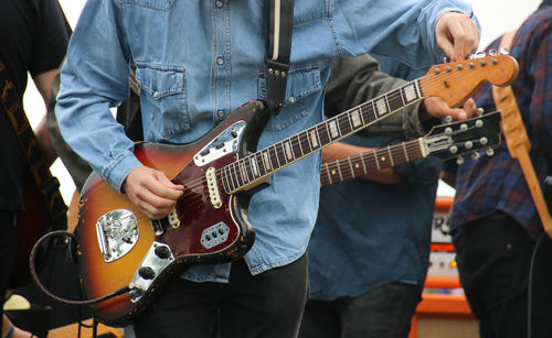 Midsection of people playing guitar on stage