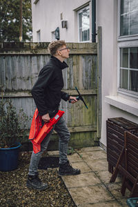 Man holding cleaning equipment while standing by built structure