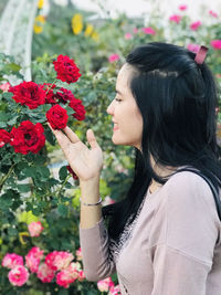 Side view of young woman smelling flowers