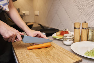 Woman chopping carrot in kitchen, close up