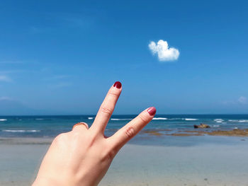 Cropped hand of woman gesturing at beach