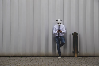 Portrait of young man standing against white wall