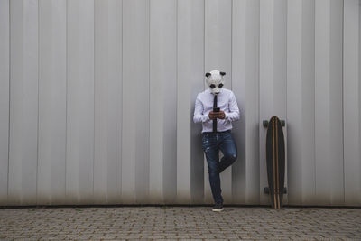 Man in white shirt, tie and panda bear mask chatting with a smartphone. space for text