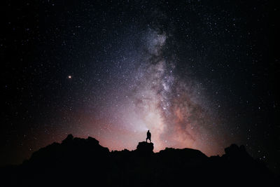 A person standing looking at the star field and the milky way