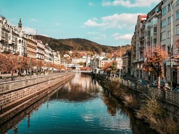 Canal amidst buildings in city against sky