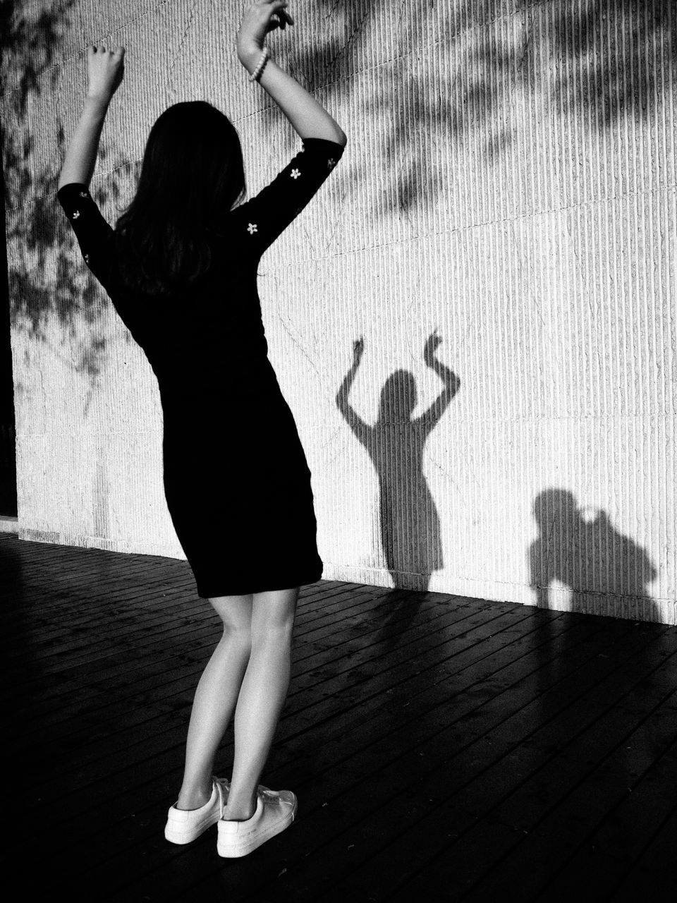 full length, shadow, lifestyles, one person, women, rear view, real people, sunlight, arms raised, human arm, day, leisure activity, adult, standing, dancing, wall - building feature, nature, outdoors, hairstyle, hand raised