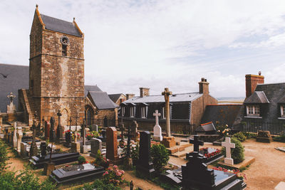 Cemetery by church against cloudy sky