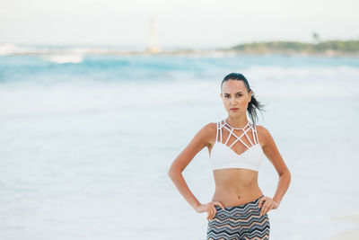 Portrait of young woman standing at beach